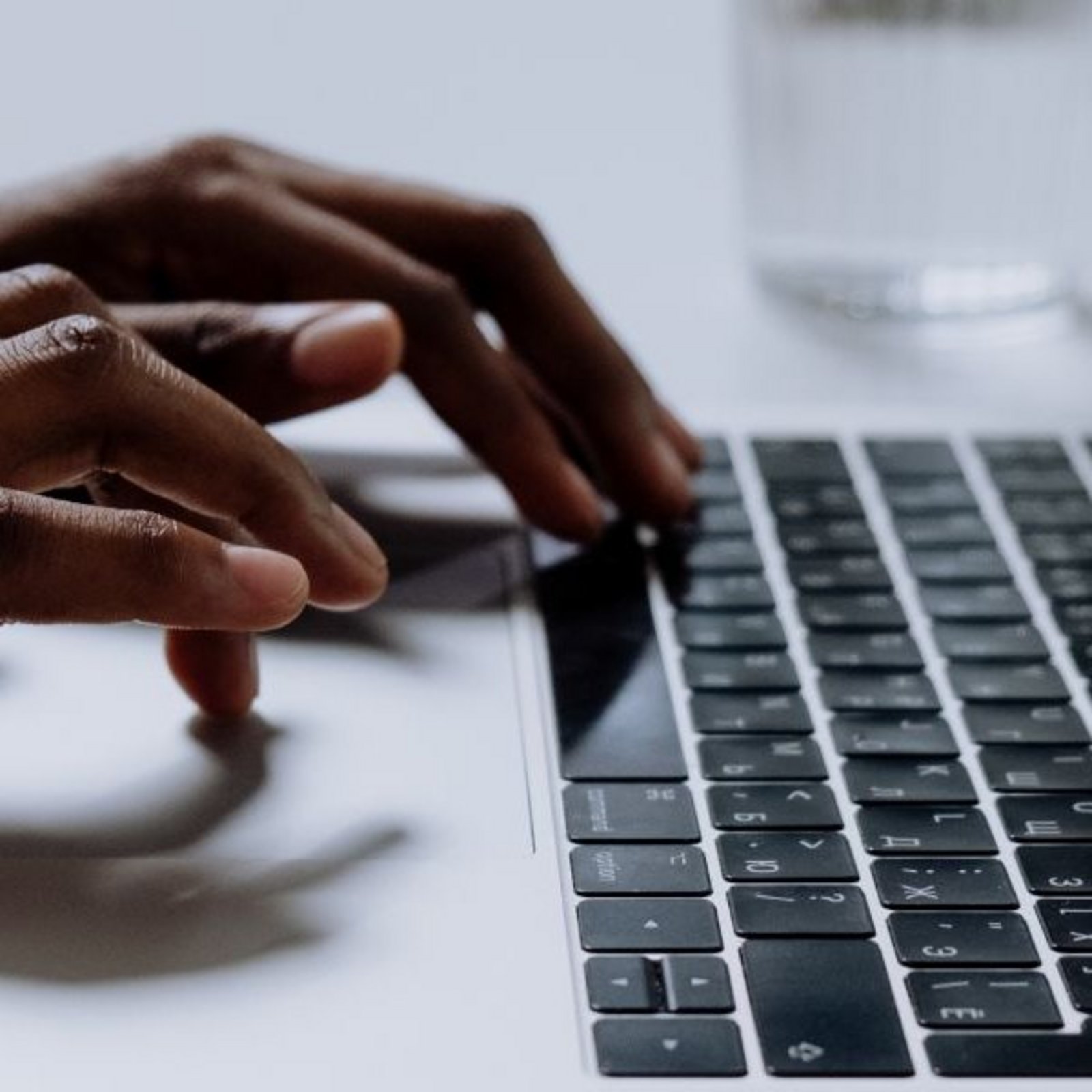 Nahaufnahme von Händen an einer Laptop-Tastatur mit dem Text: „Blogbeiträge und Interviews mit Gründer:innen“.