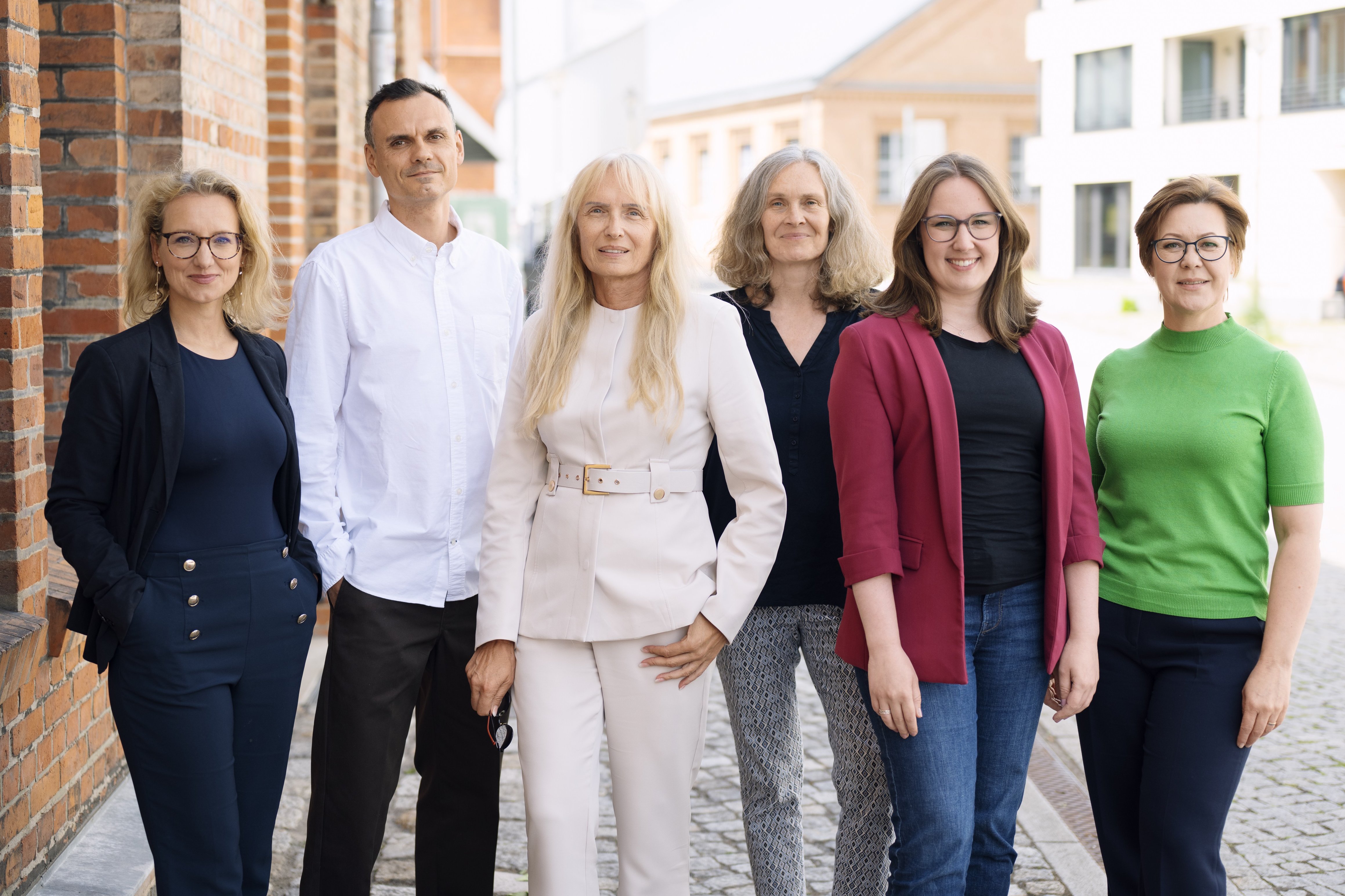 Gruppenfoto des Teams von „Perspektive: Selbstständigkeit“ im Außenbereich vor einem Backsteingebäude.